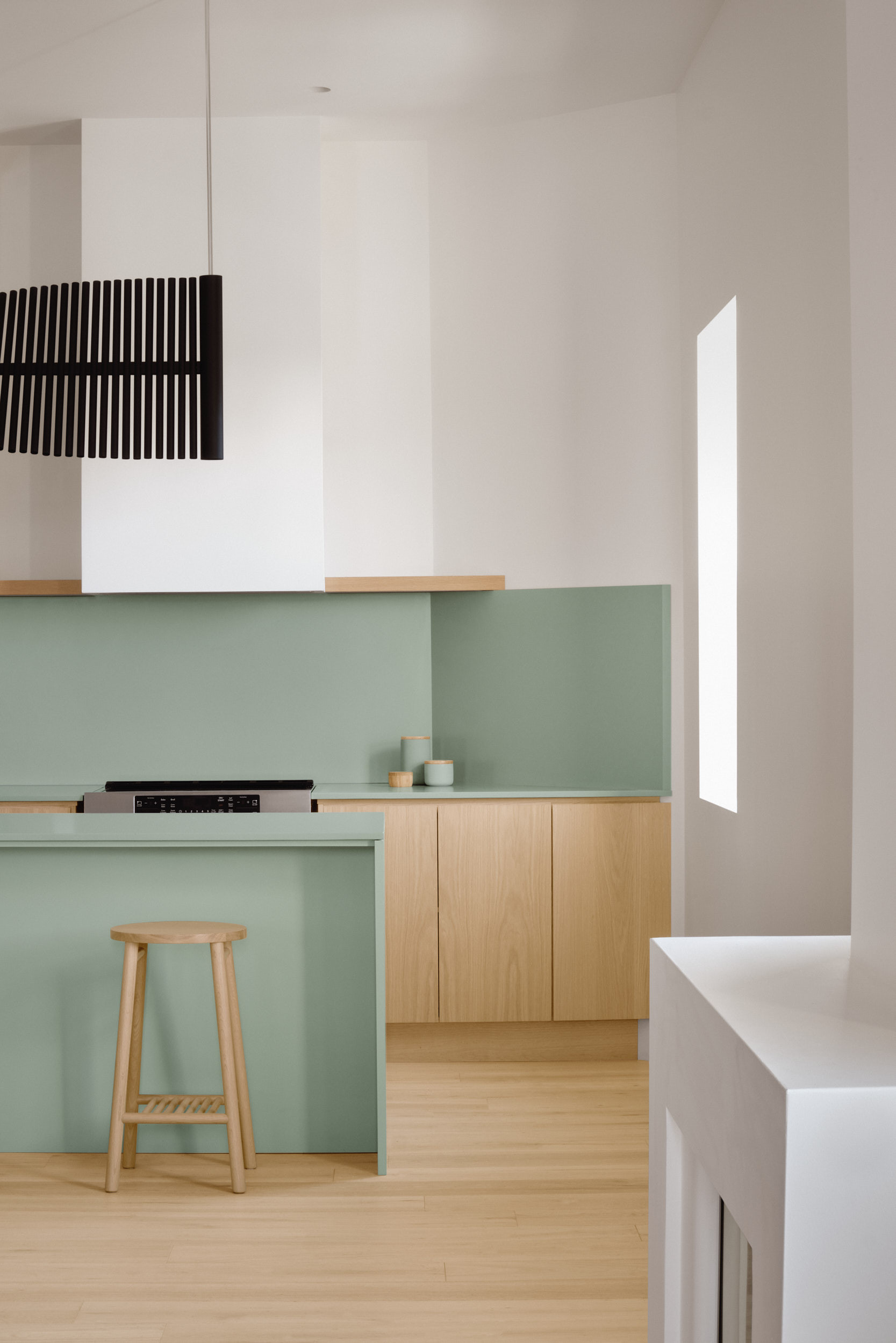 The tame stool against a sage green kitchen island