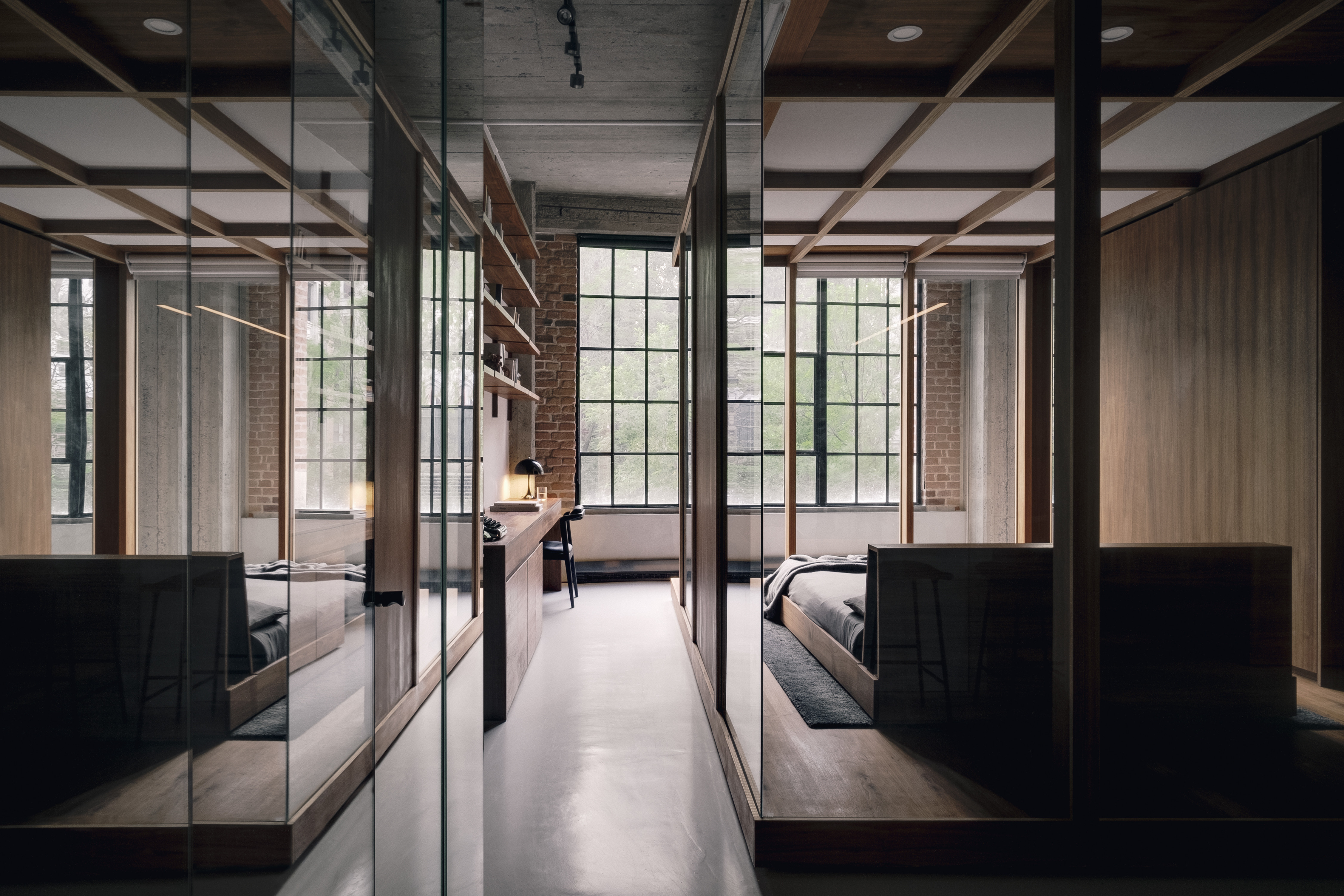 a desk area with a Nord chair next to a bedroom with glass walls