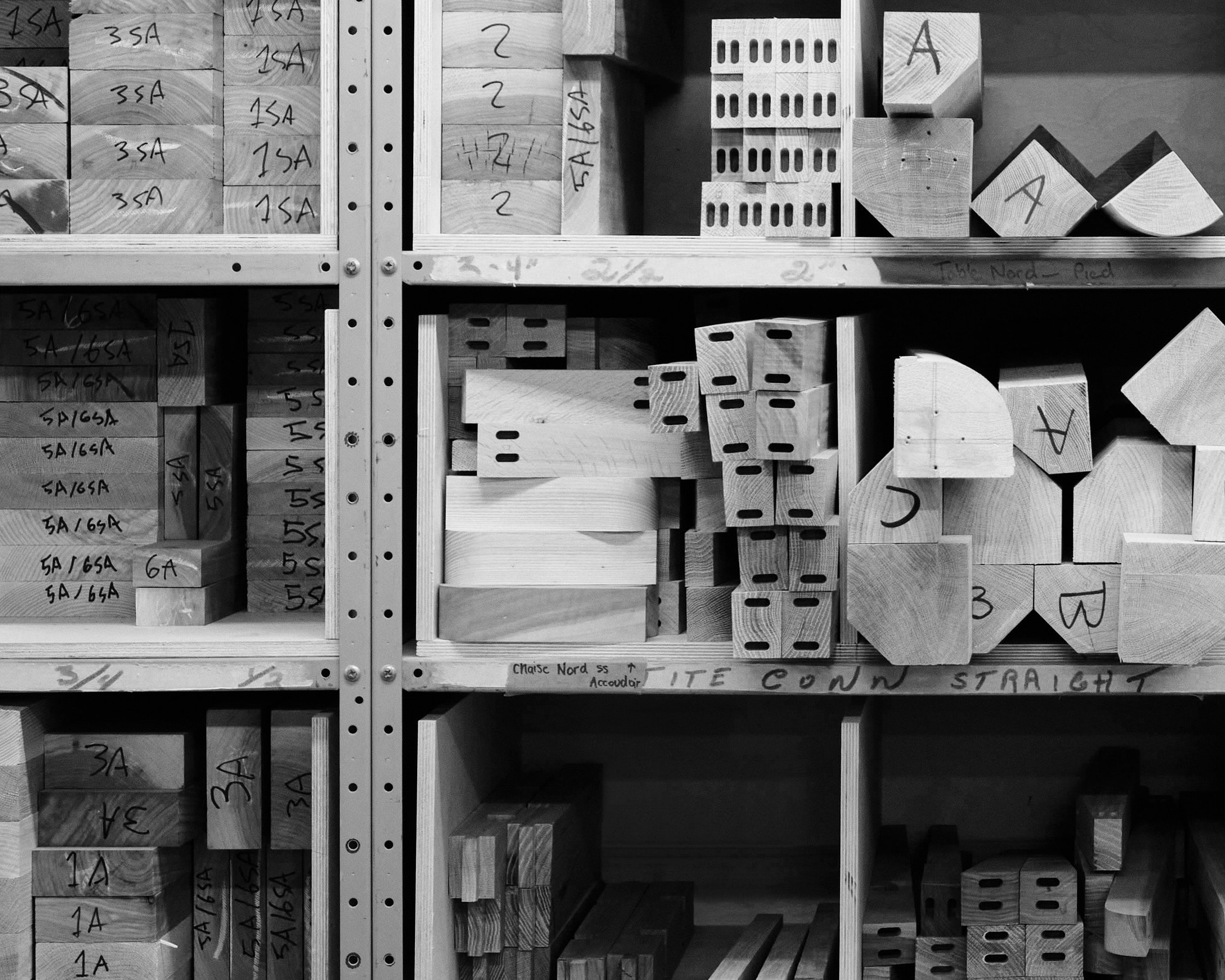 a shelf filled with various furniture parts at different manufacturing stages