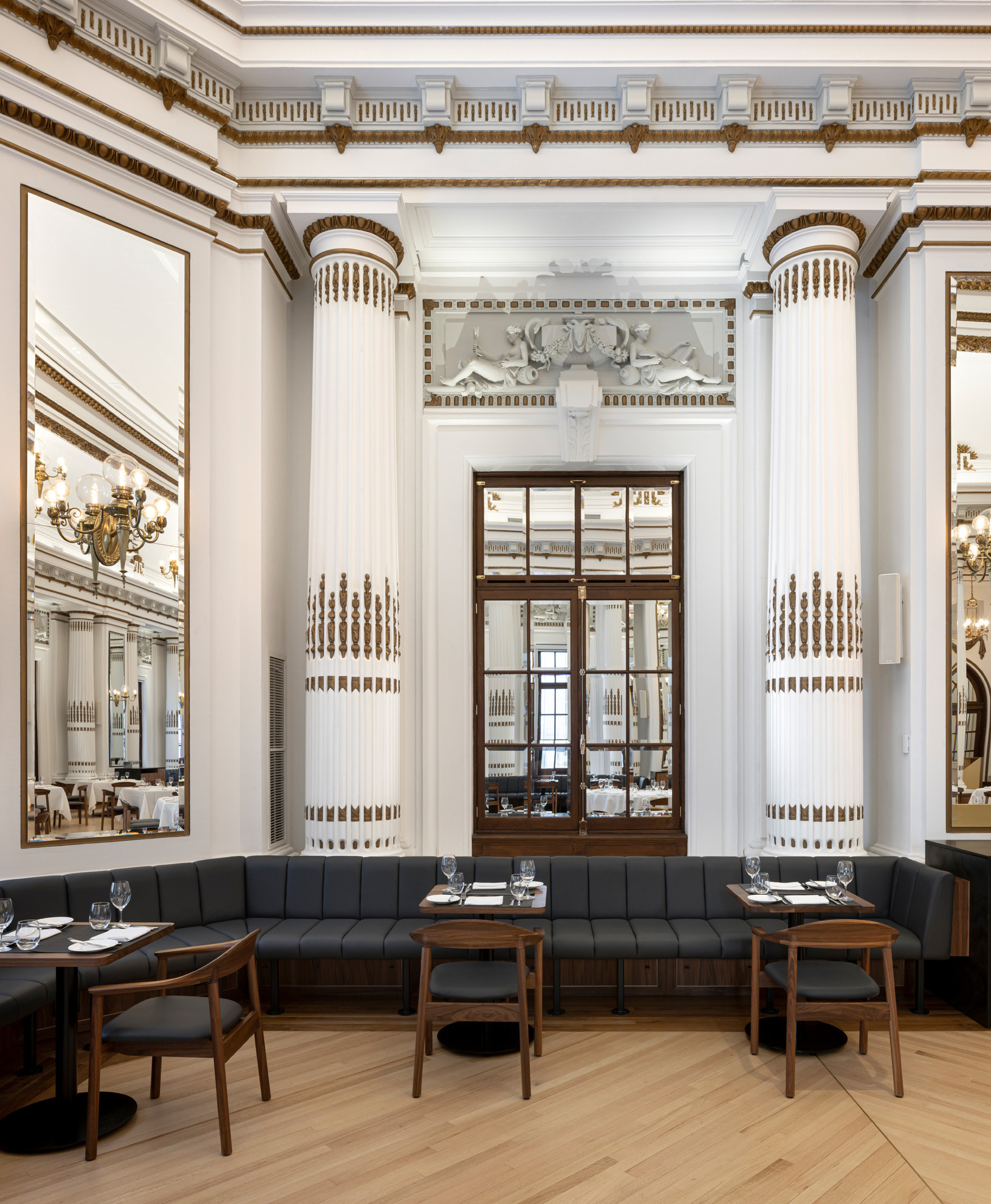 Imposing beaux arts style columns frame a mirrored window in Le Parlementaire restaurant