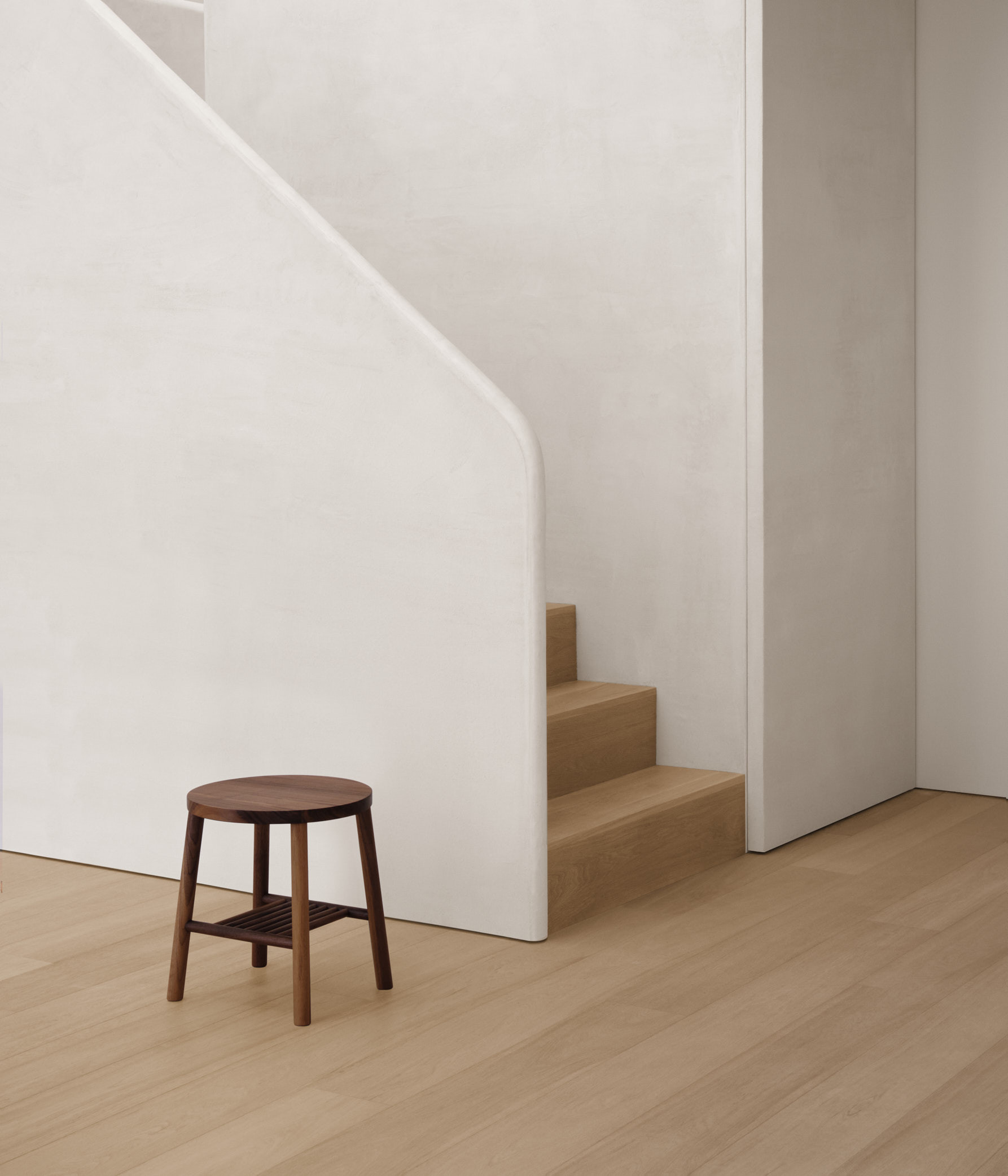 walnut stool against textured stair case