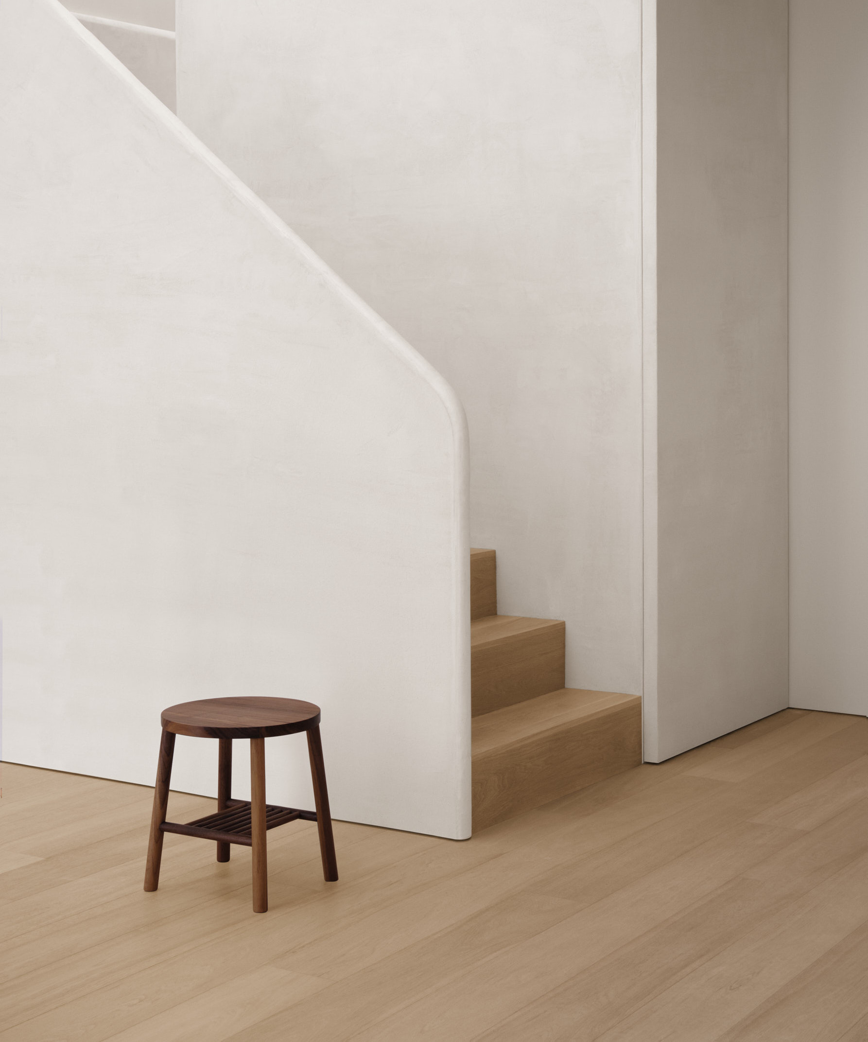 walnut stool against textured stair case